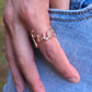 A close-up of a person's hand wearing a rose gold ring over light blue denim jeans.